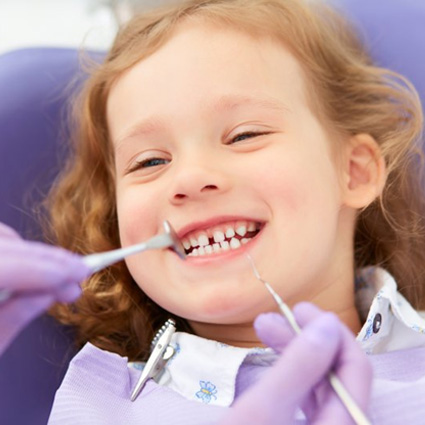 Girl smiling while hygienist starts to clean her teeth