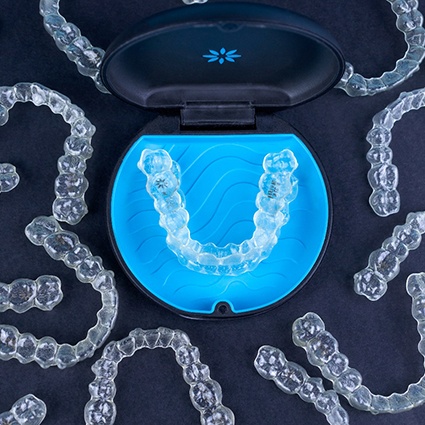 Bird’s eye view of many Invisalign trays on black background
